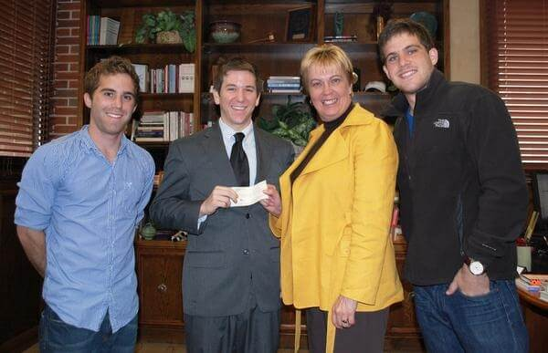 A young David Russell, second from left, presenting a donation check to the FSU College of Business, standing with two friends and the dean.